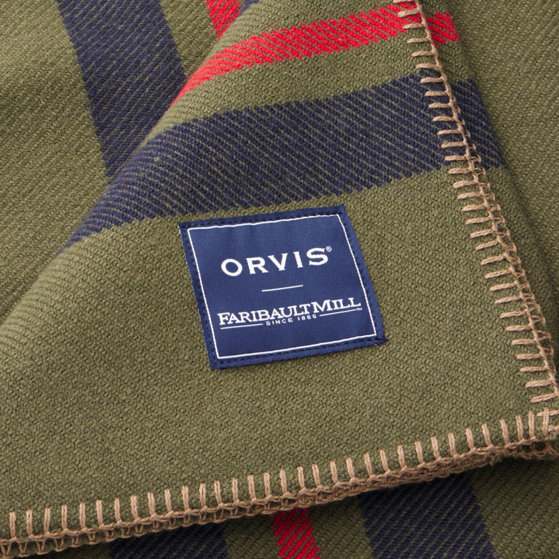 A close-up image of a finally woven olive blanket with colorful stripes.