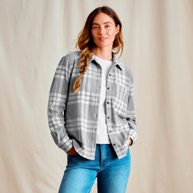 A woman wearing a gray plaid flannel shirt over a white tee.