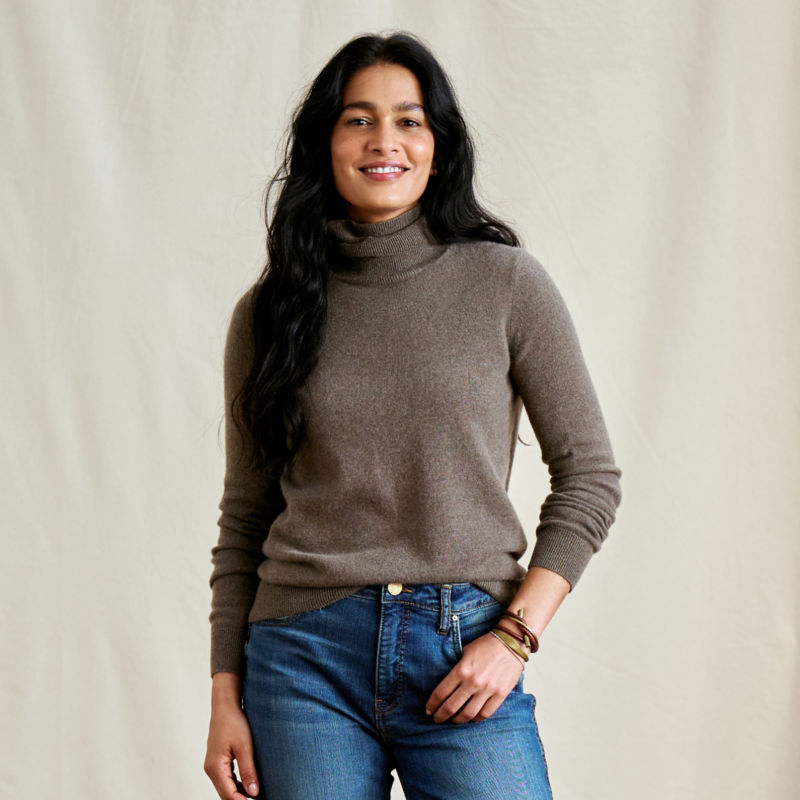 A model wearing a mushroom gray cashmere turtleneck sweater.