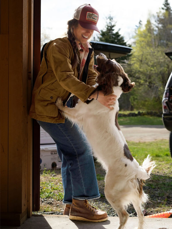 A dog jumps on a woman in a doorway.