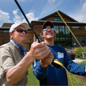 A fishing school instructor guides his student.