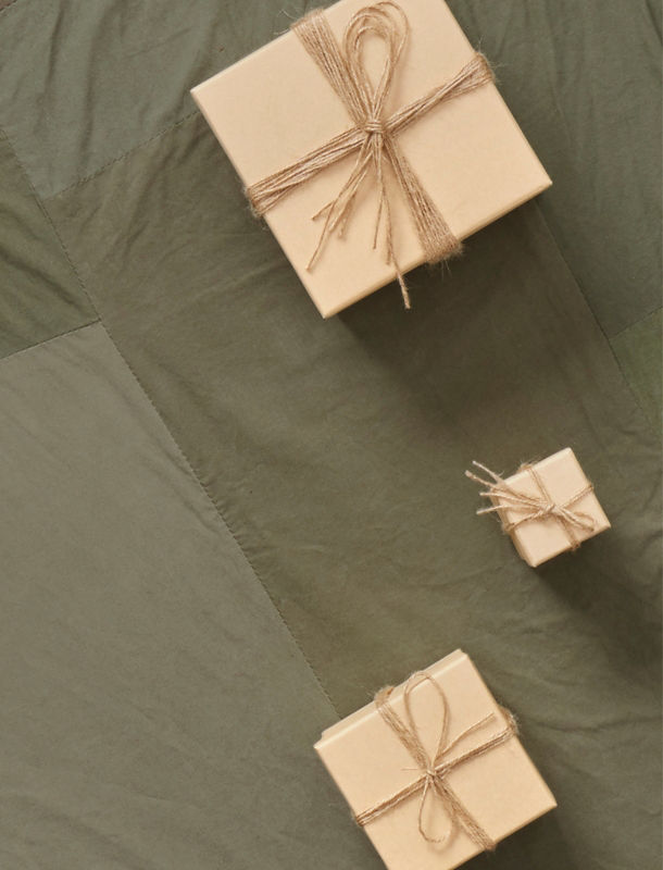 Three brown paper wrapped gifts laid on a green cloth.