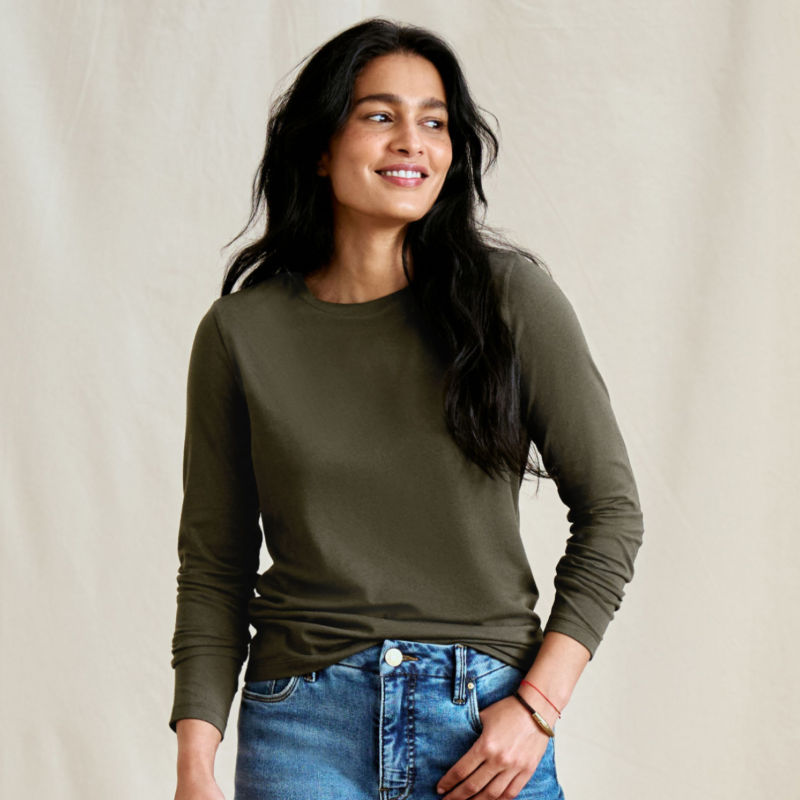 A smiling woman stands in front of a canvas backdrop wearing a green t-shirt.