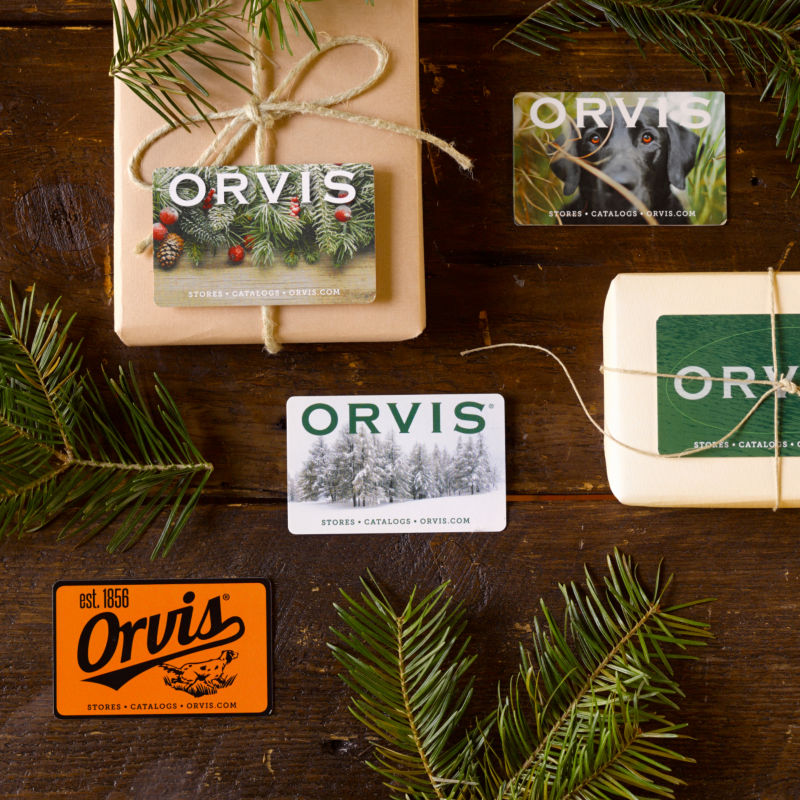 A collection of paper wrapped gifts and gift cards laid on a wooden table.