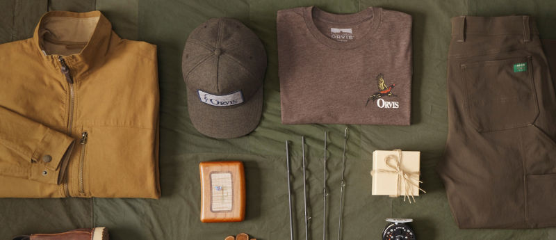 A variety of Orvis clothing and other gifts laid neatly on a green cloth.