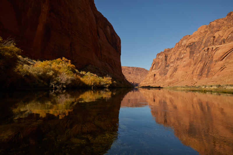 A river running through a red rock canyon under a clear blue sky