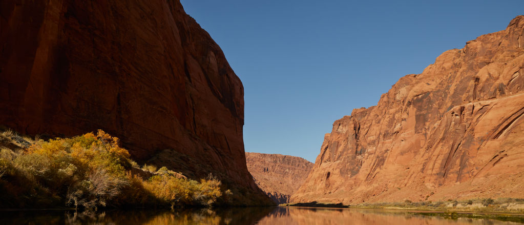 A river running through a red rock canyon under a clear blue sky