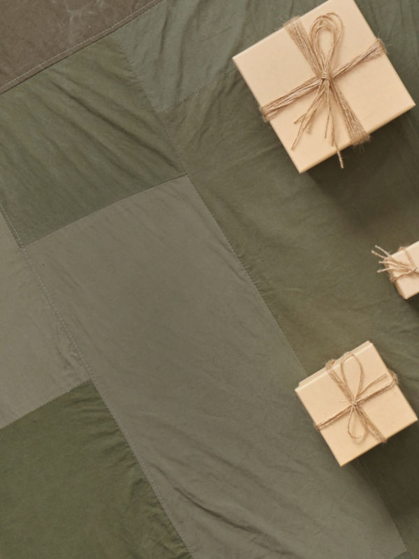 A hiker sits on a wooden deck offering a water bottle to someone off camera.