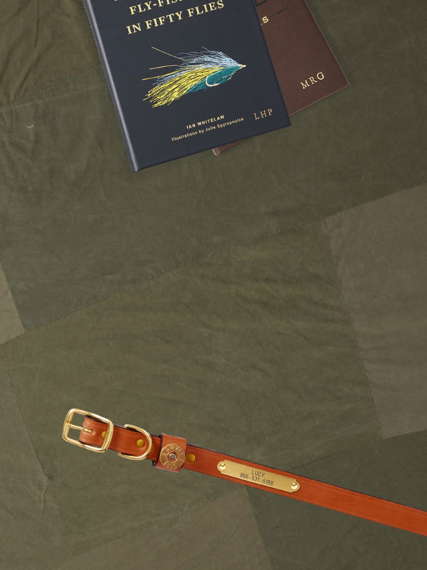 A hiker sits on a wooden deck offering a water bottle to someone off camera.