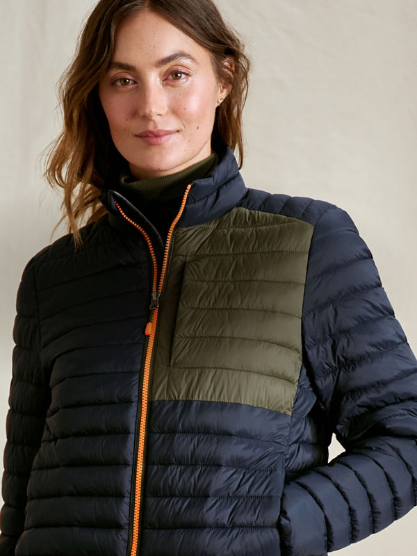 A model wearing a color-blocked olive and navy quilted jacket with an orange zipper.