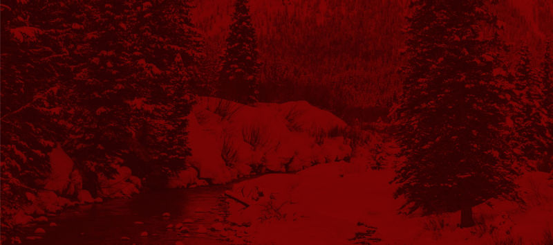 A landscape of a stream running through a snowy forest with a red filter.