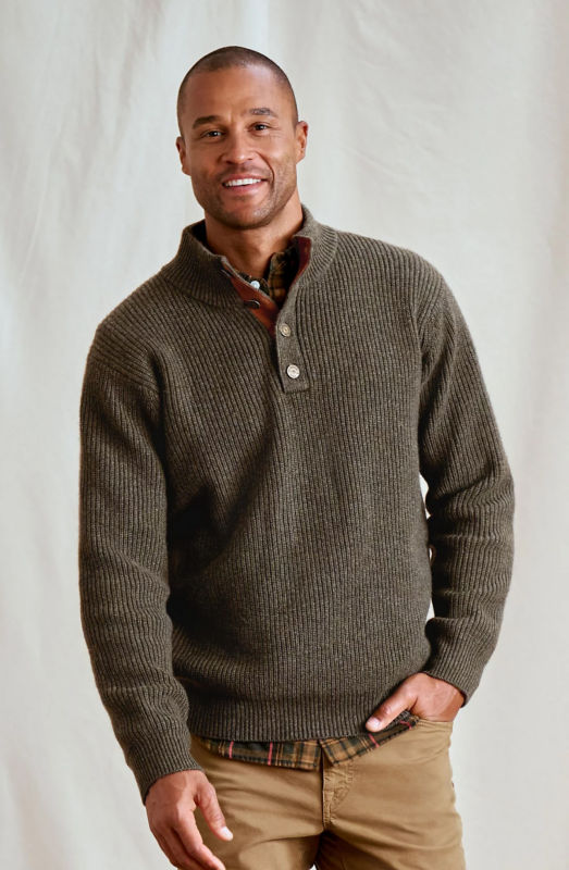A smiling man wearing a brown pullover with tan pants.