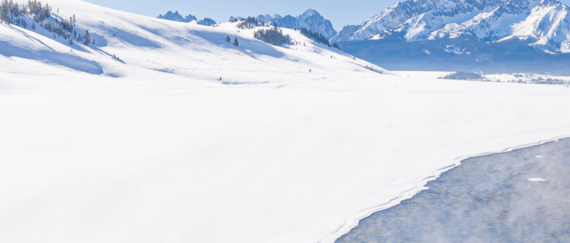 Snowy mountains with river running through it.