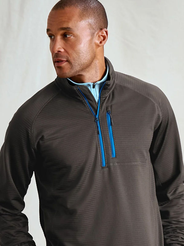 A detailed image of a model wearing a gray pullover with blue zippers.