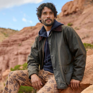 Man in a Barbour Classic Bedale Jacket looks out from a desert rocky outcropping.