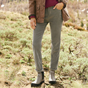 Woman in Sagebrush Stretch Corduroy Natural Fit Skinny-Leg Pants walks along a ridgeline in a snowy countryside.