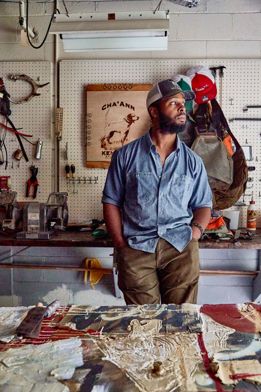 Man in hat stands in gear workshop
