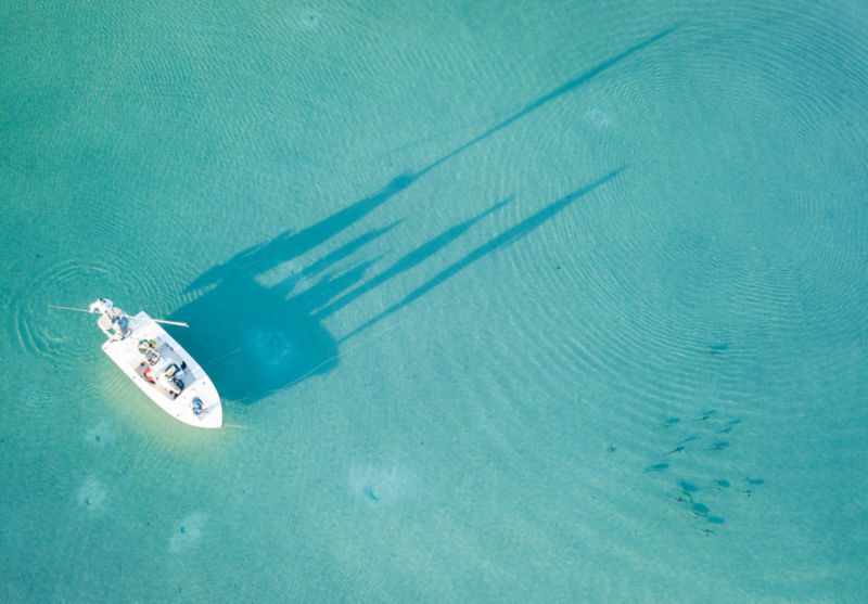 A drone-view of a skiff on the turquoise flats of the Bahamas.
