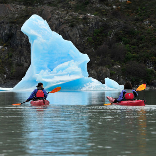 2 anglers kayaking toward an iceberg