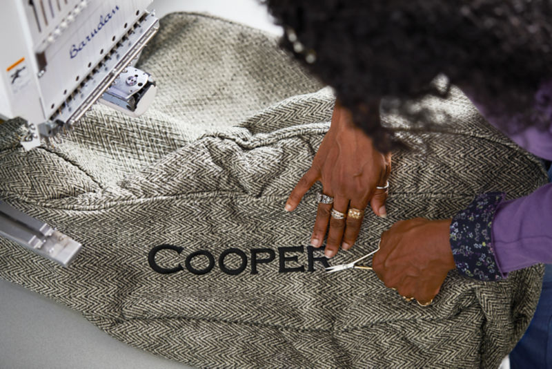 Hands at work sewing on personalization on a dog bed.