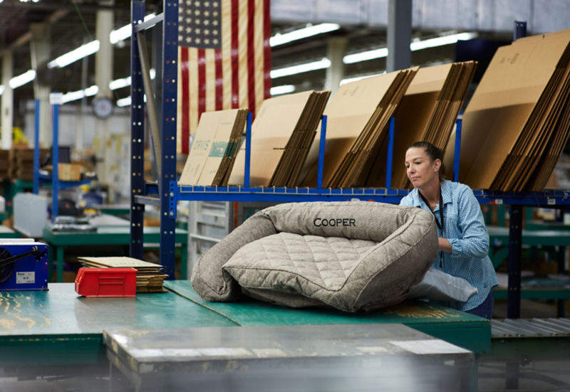 A woman handling an Orvis dog bed in a warehouse.