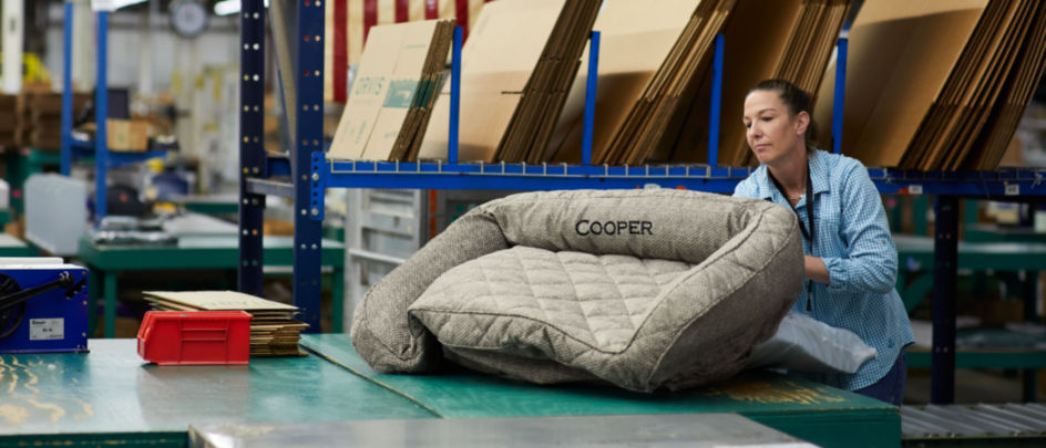 A woman handling an Orvis dog bed in a warehouse.