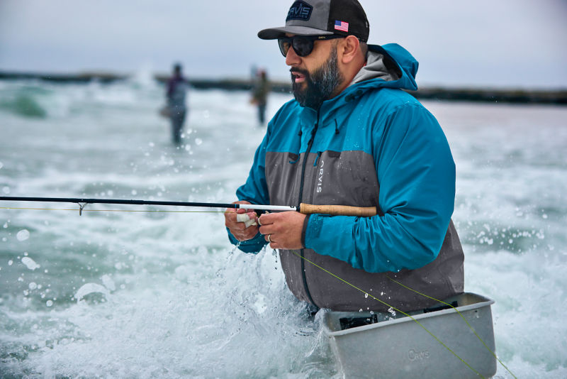 An angler waist-deep in the ocean.