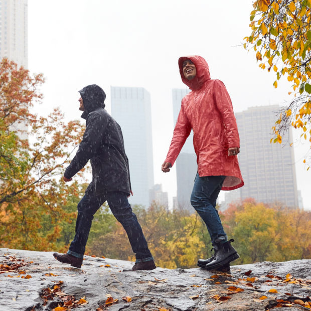 A man and a woman wearing rain coats walking in the city in the rain
