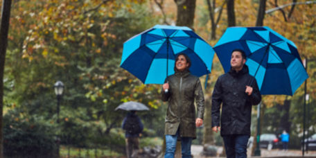Two people waling in the rain with blue striped umbrellas