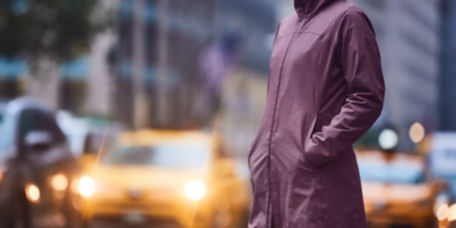 A woman standing in a city street wearing a iced grape raincoat.