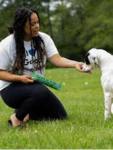 A woman feeding her dog a treat outside on the grass