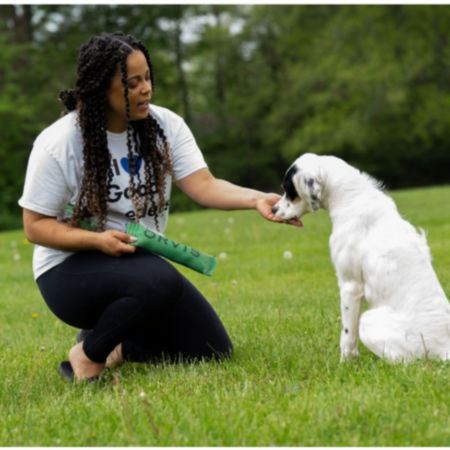 Melinda kneeling in the grass training her dog