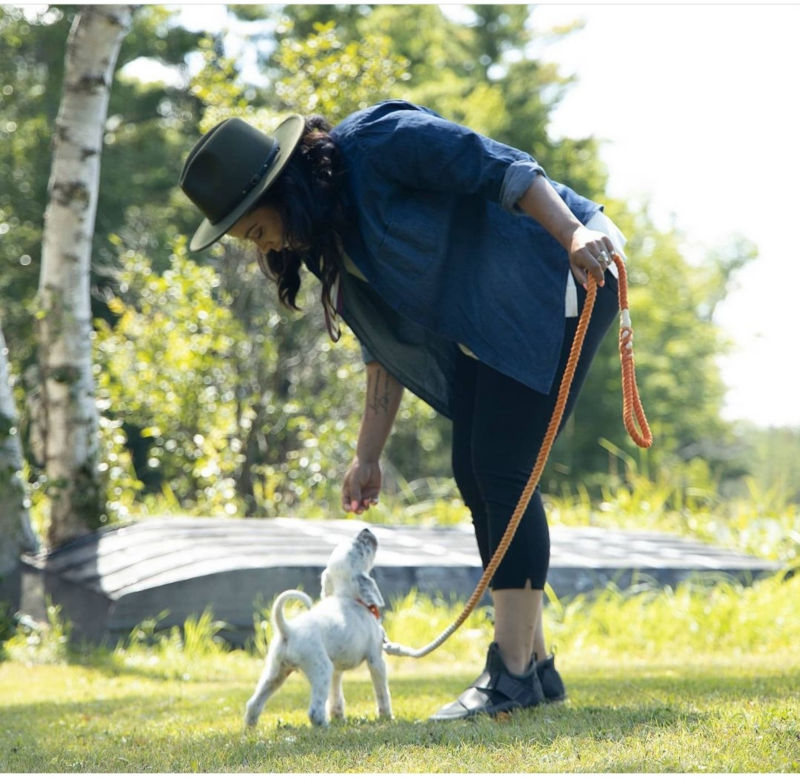A dog trainer gives a small white puppy a dog treat.