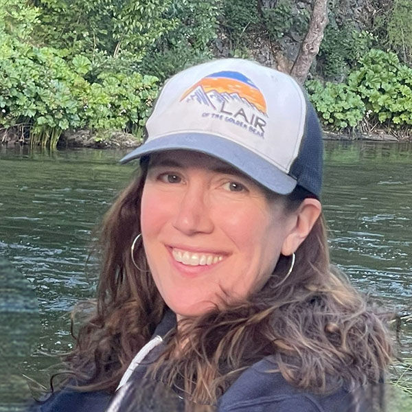Carla Feely sits outside by a green river.