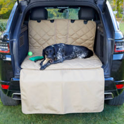A dog laying in the back of a car on a Grip-Tight® Quilted Hose-Off Cargo Protector