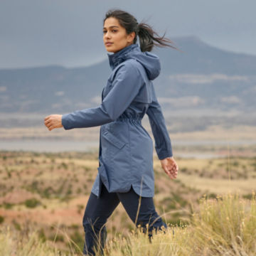Woman in Pack N Go Jacket walks through tall grass in the desert.