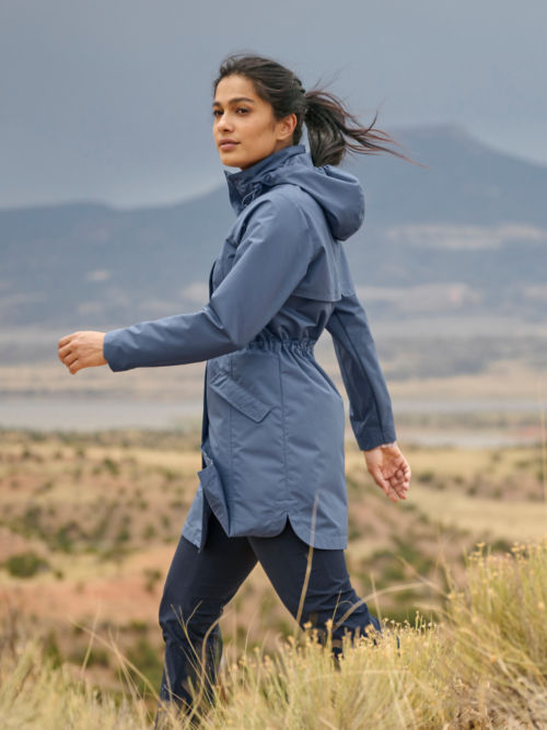 A woman in a Dusk Pack n Go Jacket walks through long grass in the desert.