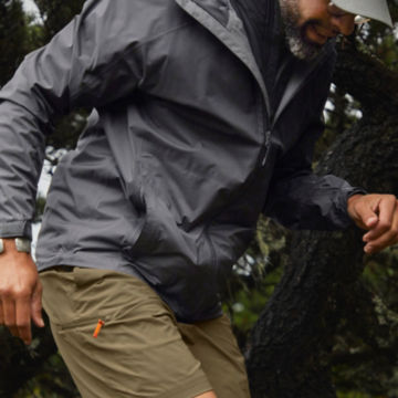 A man in a Men's Ultralight Storm Jacket hops down a trail.