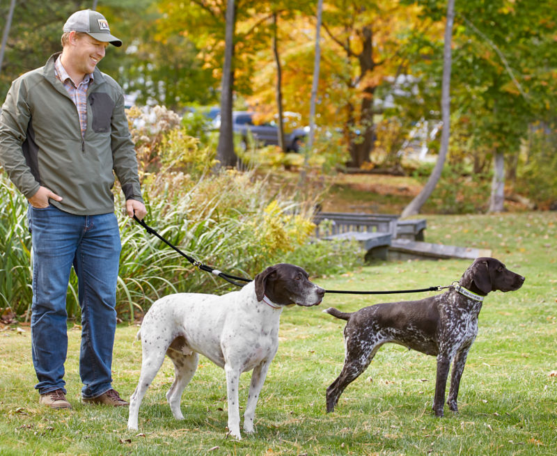 A man standing outside holding two dogs on a leash