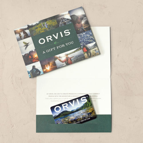 An Orvis Gift Card ticked into its card pocket laid on a wooden background. 