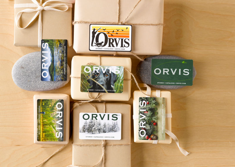 Orvis gift cards arranged on top of kraft paper covered packages tied with twine.