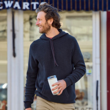 Man in Navy Waffle Hood Wool/Cashmere Pullover walks out of a store with a YETI cup.