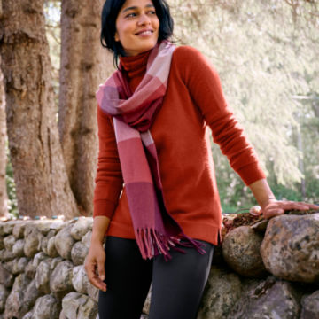 Woman in Classic Cashmere T-Neck leans on a rock wall in the woods.