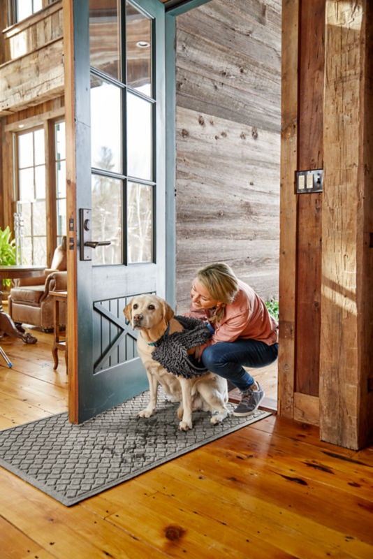 A woman wiping off her wet dog with a microfiber towel by the door entryway