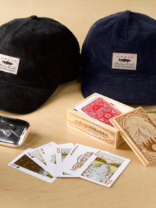 An assortment of gifts including baseball hats, playing cards, and small items that make good stocking stuffers on a wood background