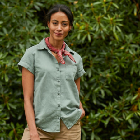 model standing in front of large rhodedendron wearing a green button down short sleeved shirt