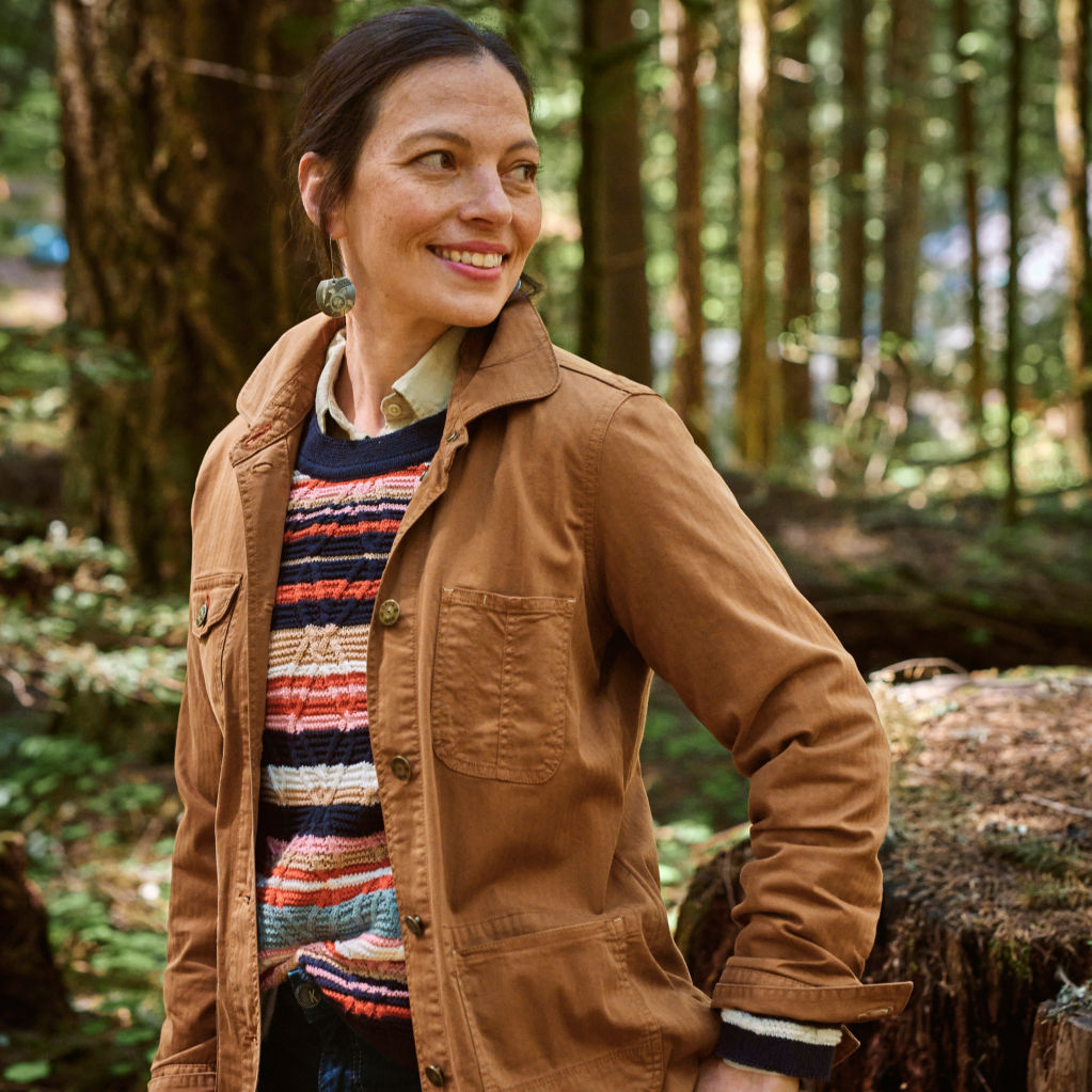 Woman walks through the woods in a Herringbone Chore Jacket.