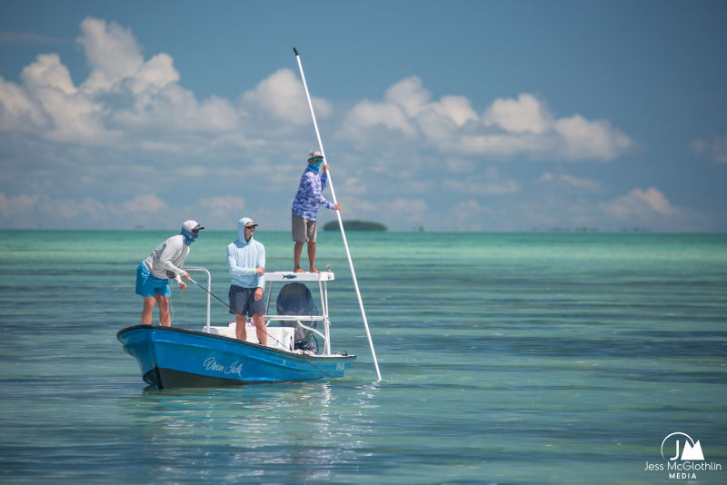 Three anglers on a skiff fly fishing in the clear turquoise waters off Belize.