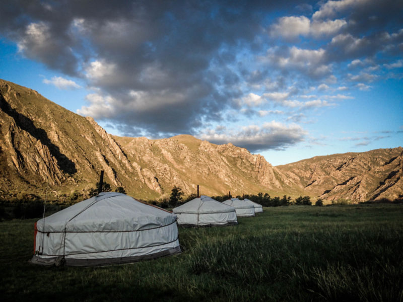 Yurts in Mongolia surrounded by bare mountains.