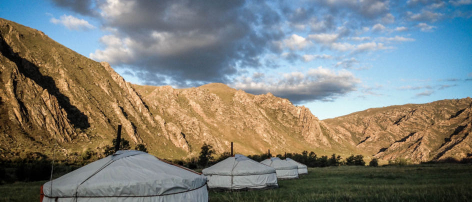 Yurts in Mongolia surrounded by bare mountains.